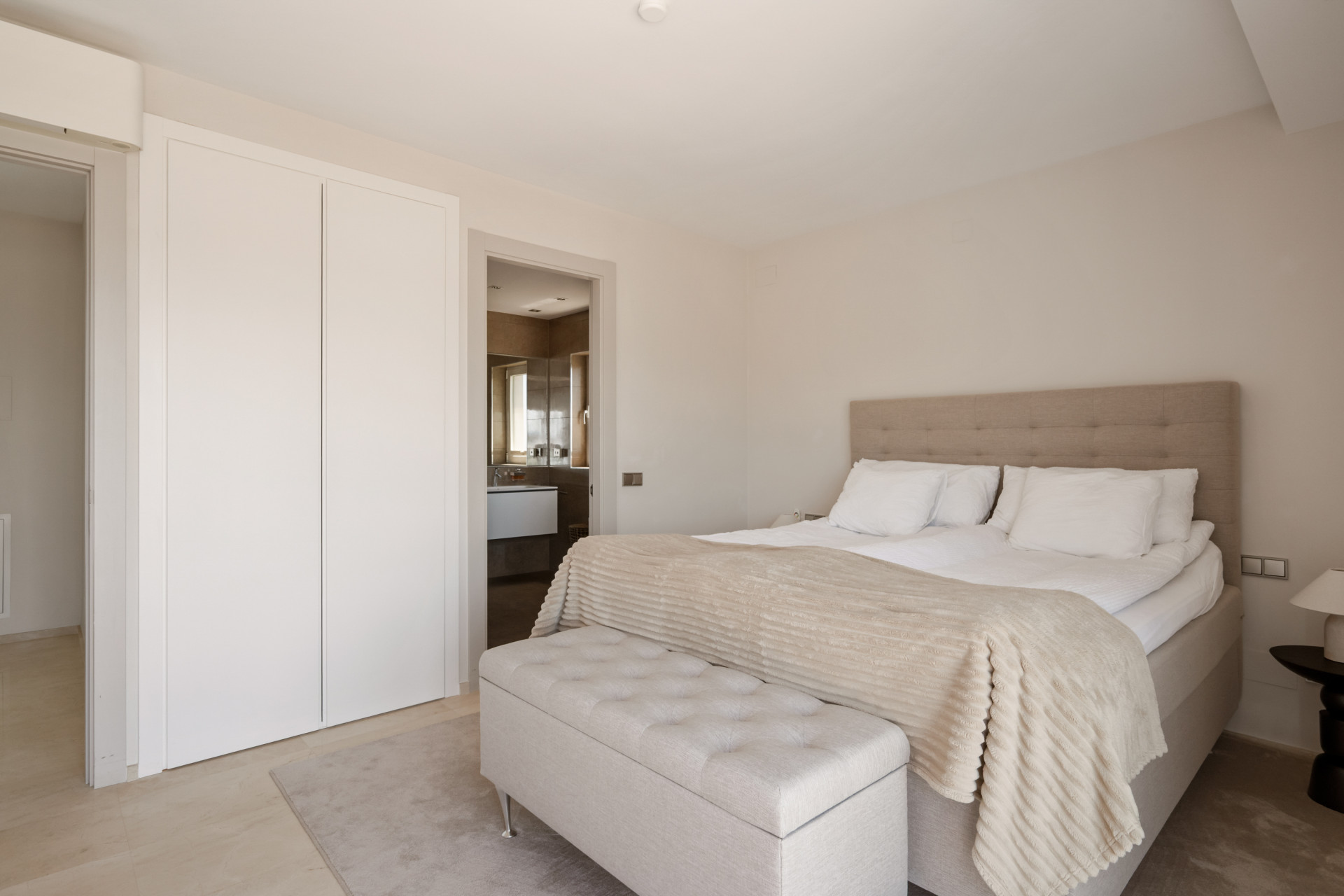 Spacious bedroom with seating area and an en-suite bathroom visible through the doorway.