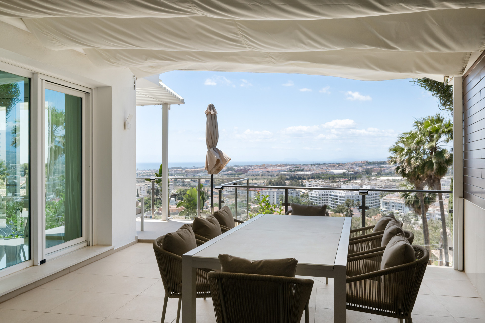 Terrace view featuring a dining set and coastline in the background.