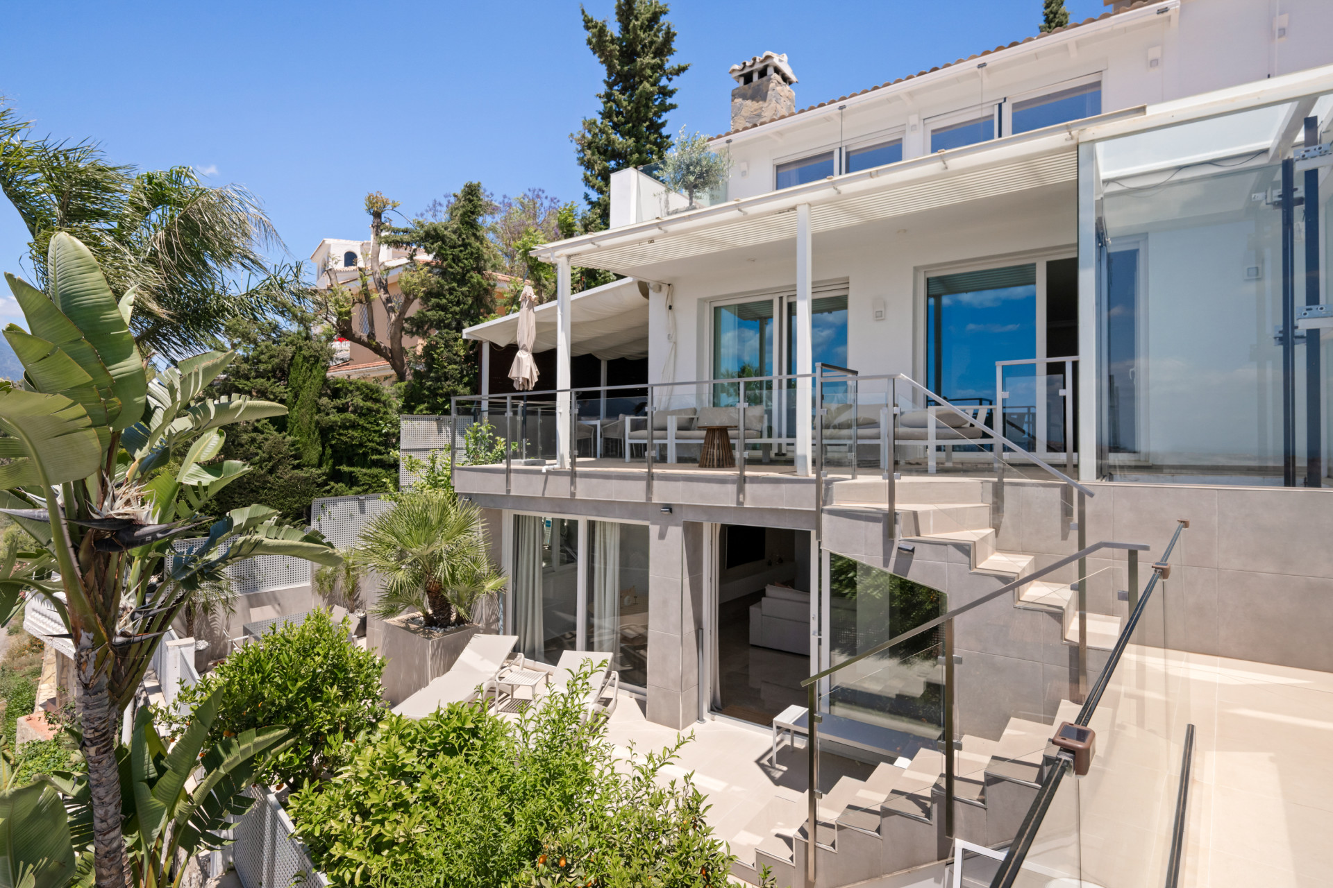 An exterior view showing a multi-level villa with outdoor seating and lush landscaping.