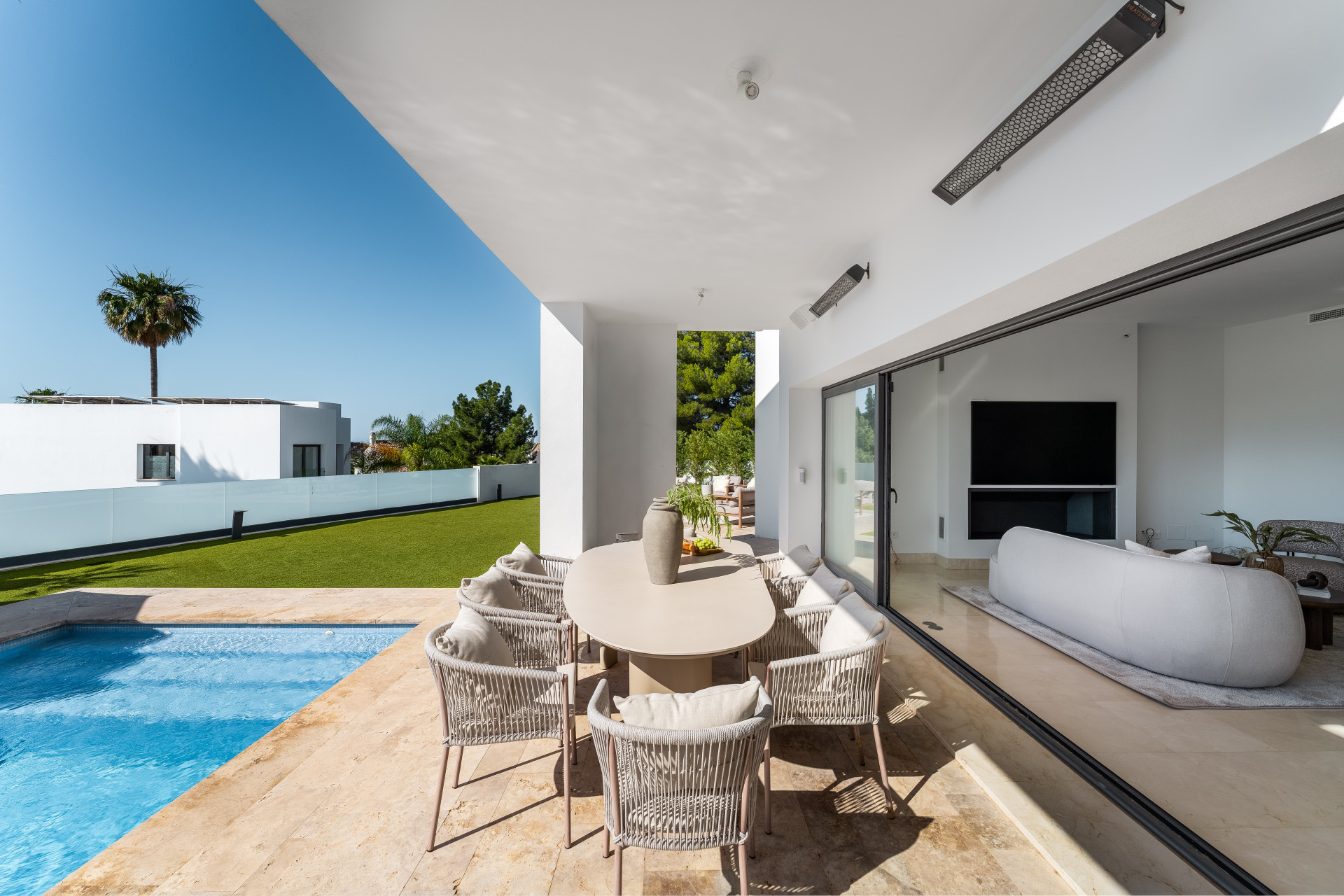 Dining area outdoors with a view of the pool, featuring a large table and stylish chairs.