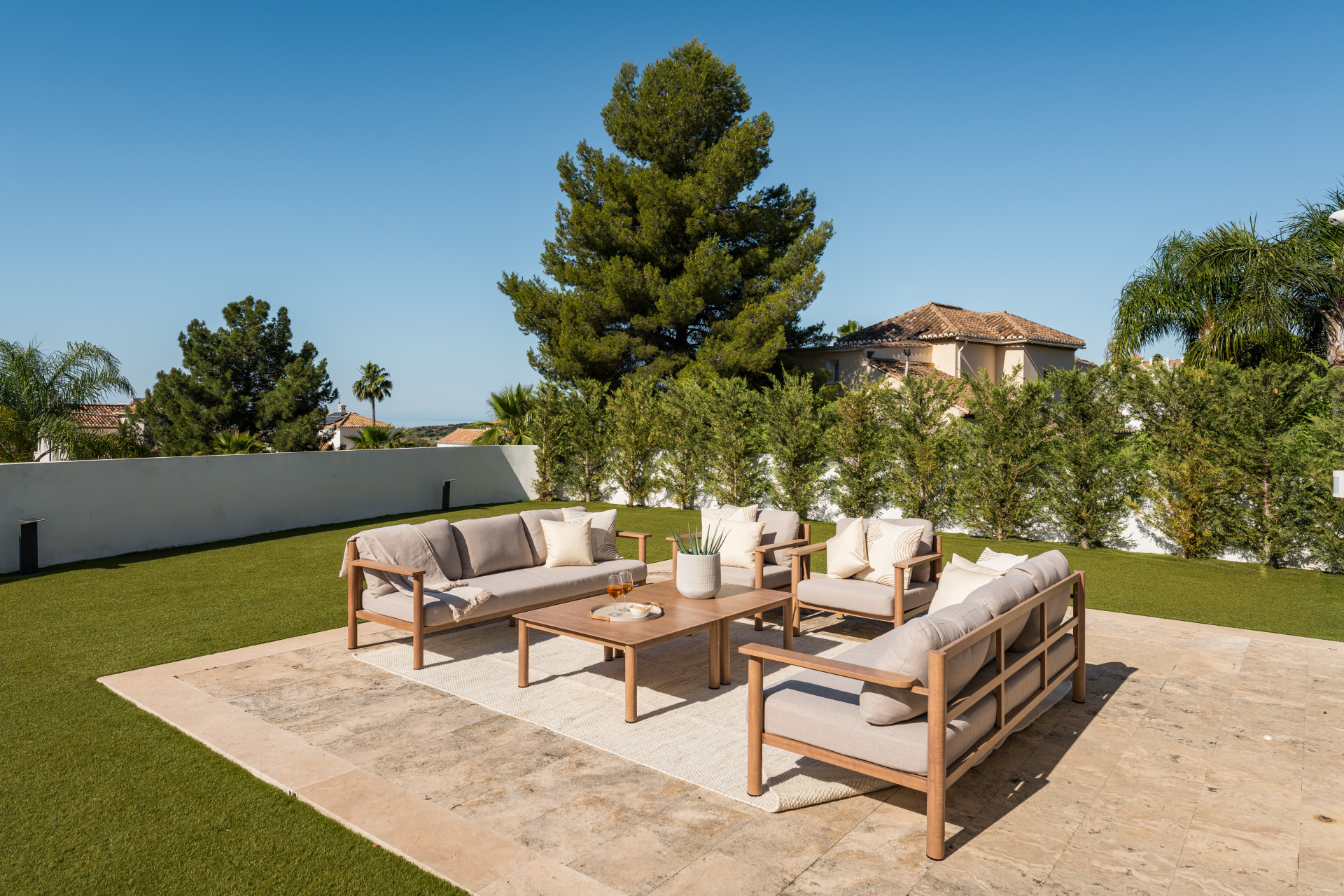 Wide angle of the seating area, showcasing greenery and bright sunlight overhead.