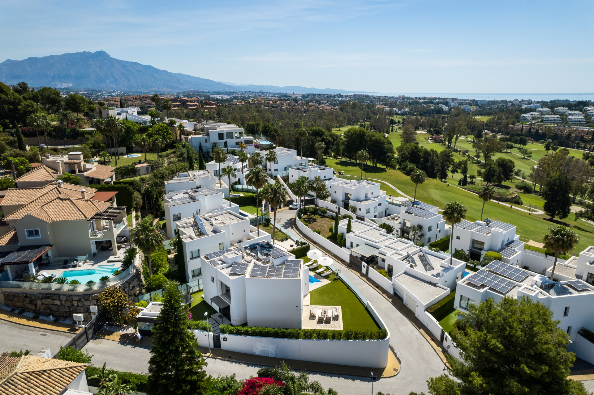 Panoramic view of the villa area with lush greens and numerous solar panel rooftops.
