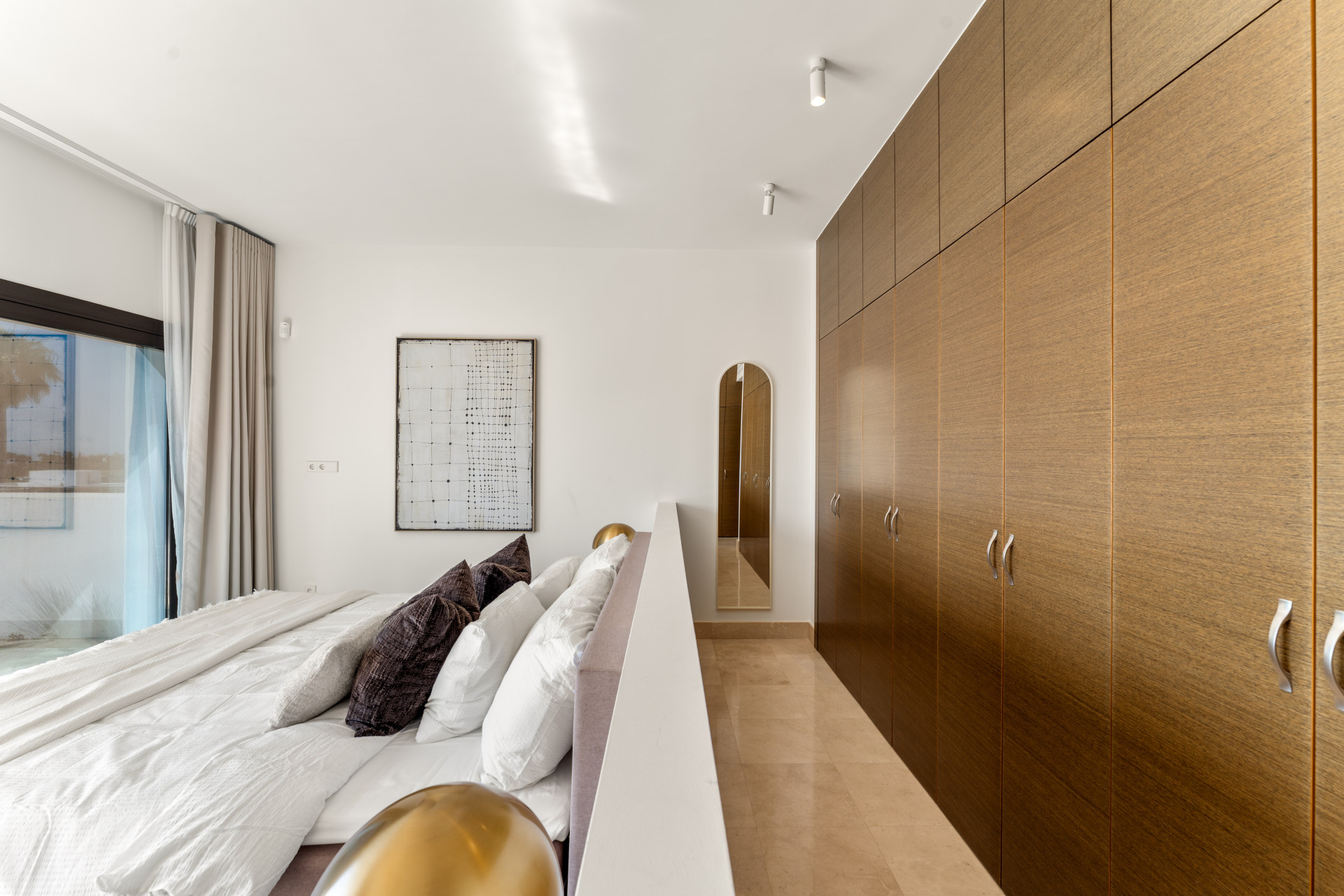 Modern bedroom with a large bed, decorative pillows, and a built-in wardrobe.