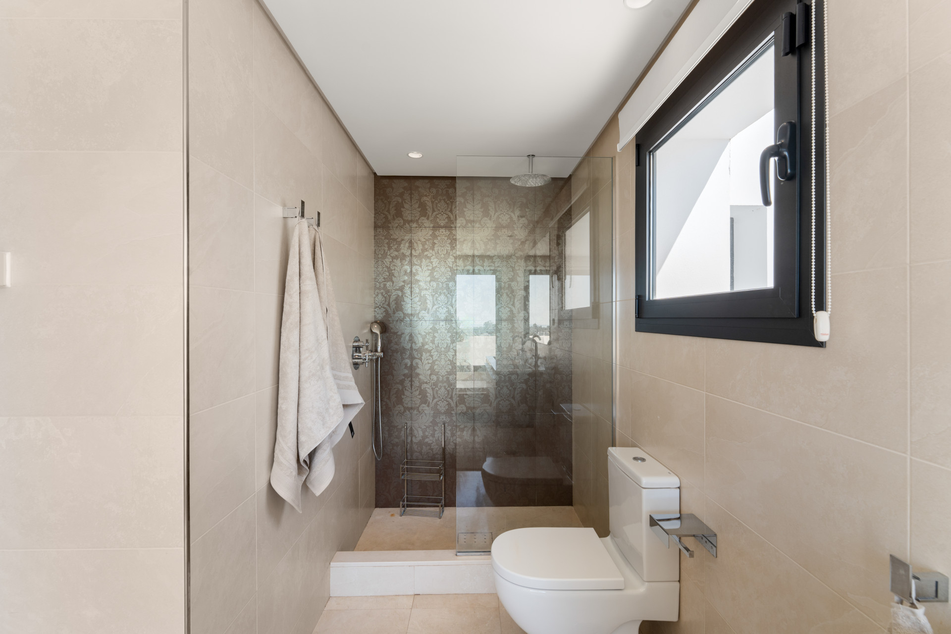 Bathroom featuring a glass shower enclosure and neutral tile.