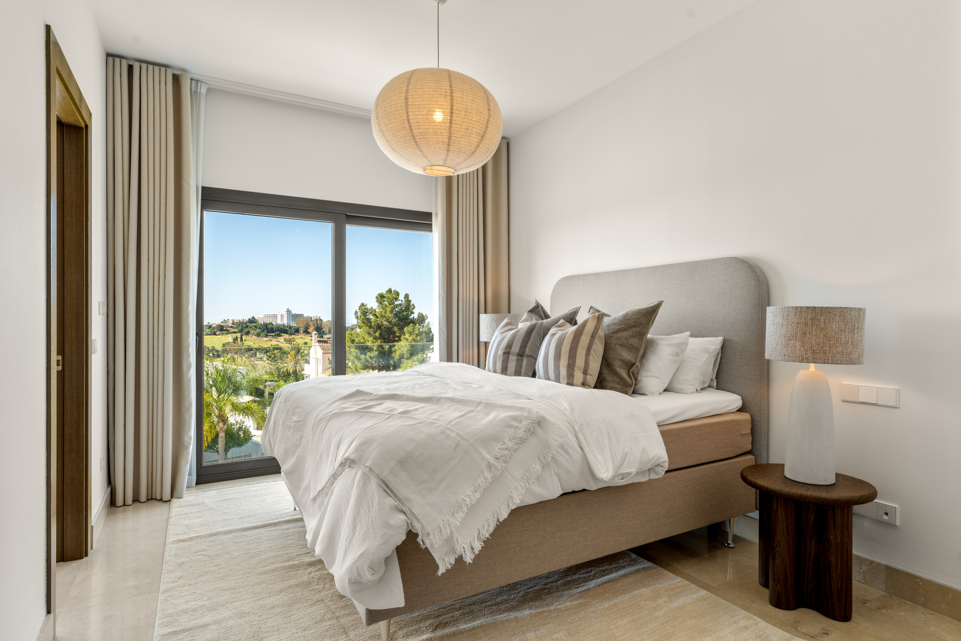 Cozy bedroom featuring a large bed, decorative pillows, and window view.
