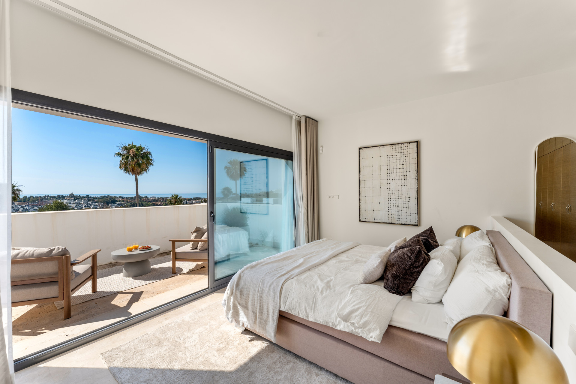 Bedroom with a terrace view, equipped seating, and decorative art pieces.