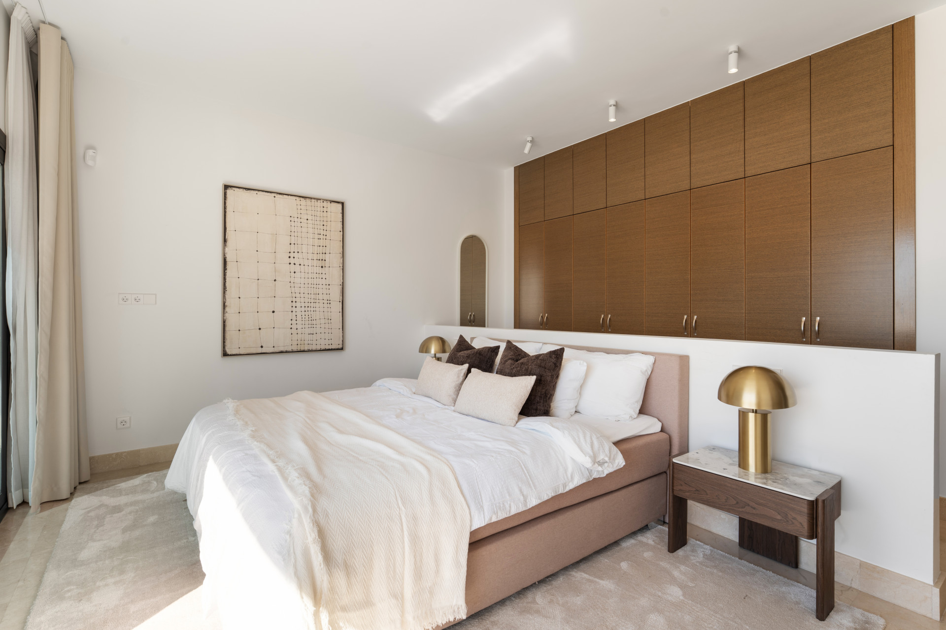 Cozy bedroom featuring a bed, artwork, and built-in storage.