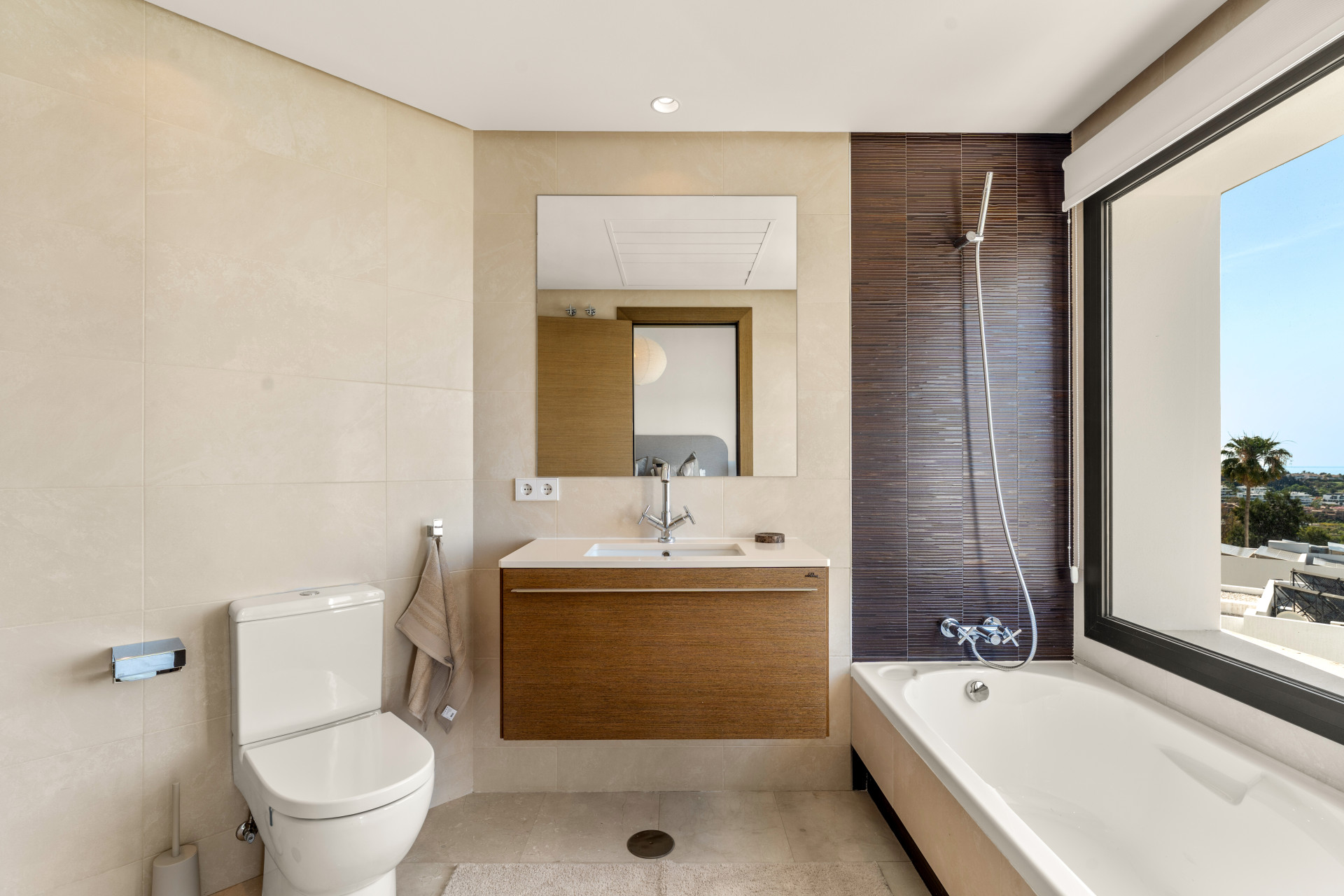 Well-lit bathroom with modern fixtures, tub, and wall tiles.