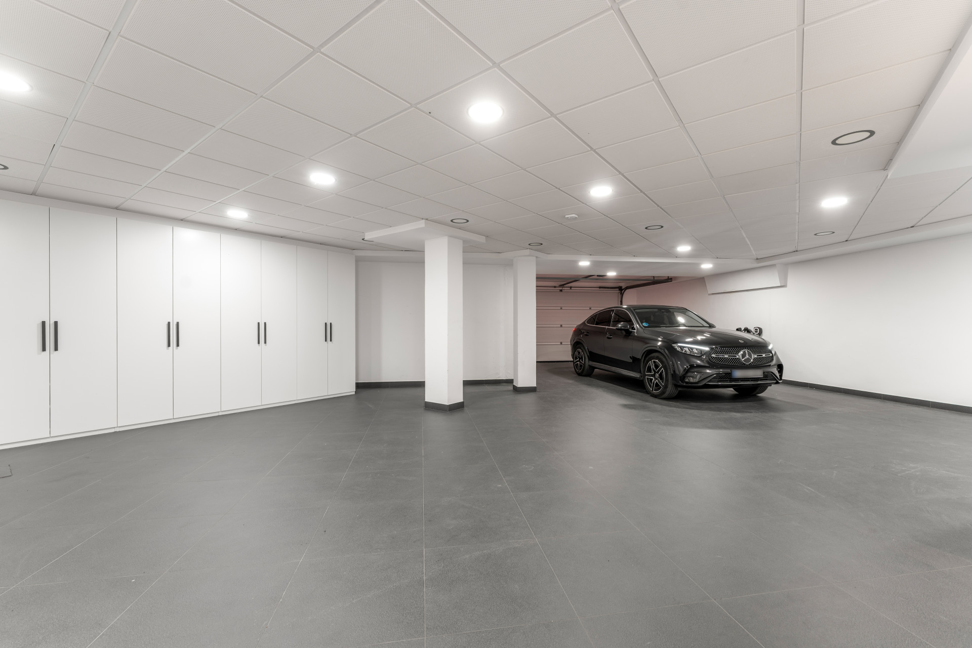 Garage with a black car and white cabinets