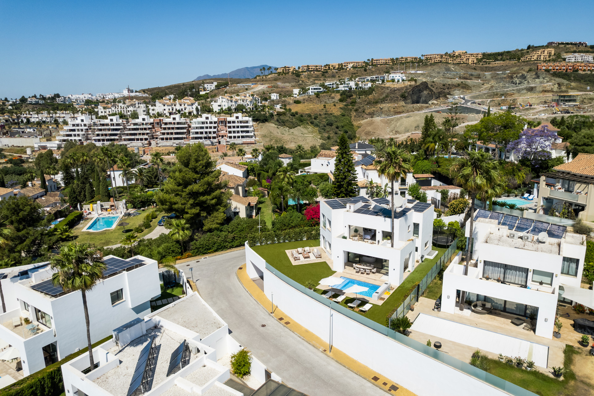View of multiple villas in a hillside community, showcasing golf course and mountains in the background.
