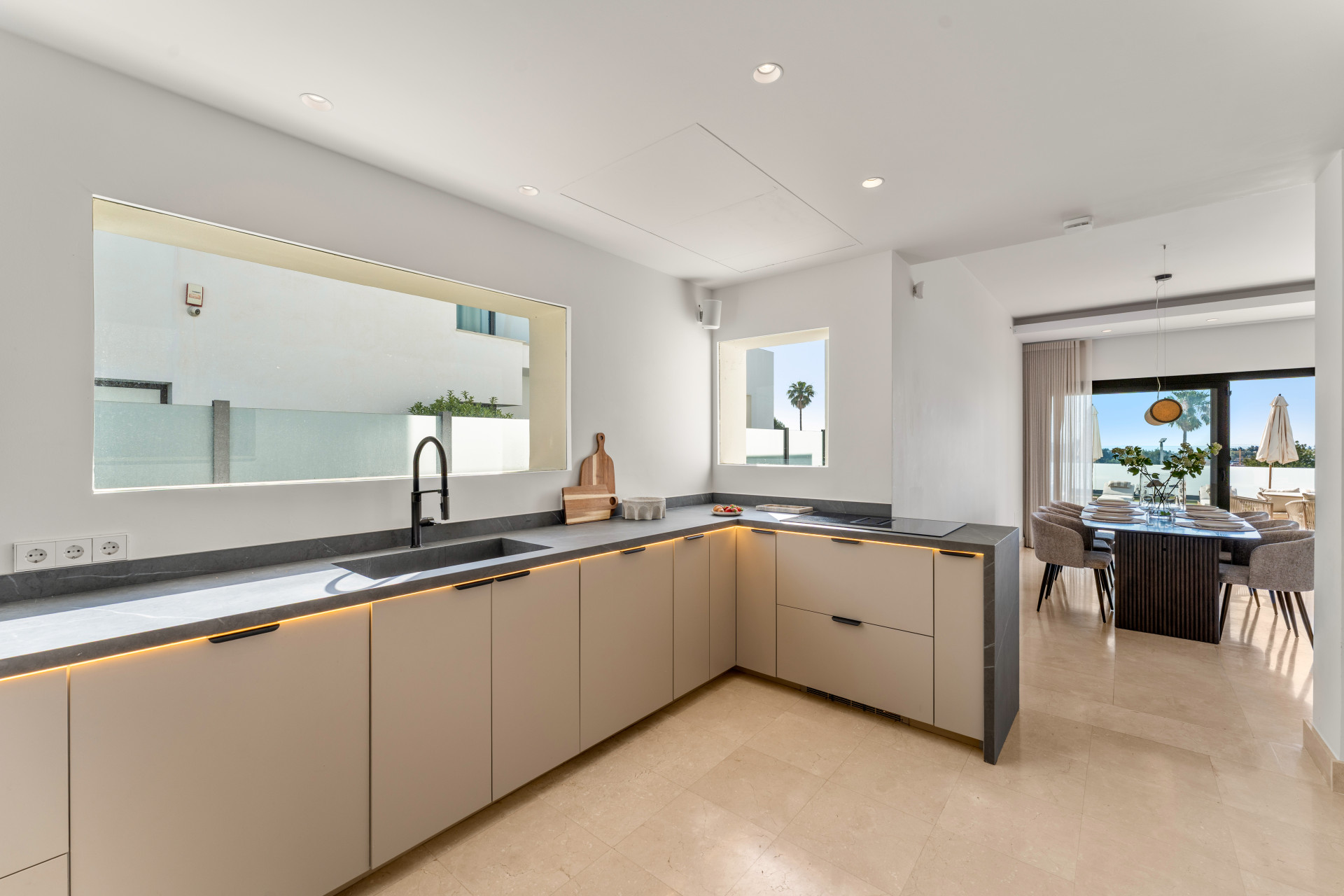 Modern kitchen showcasing sleek cabinetry and a large window.