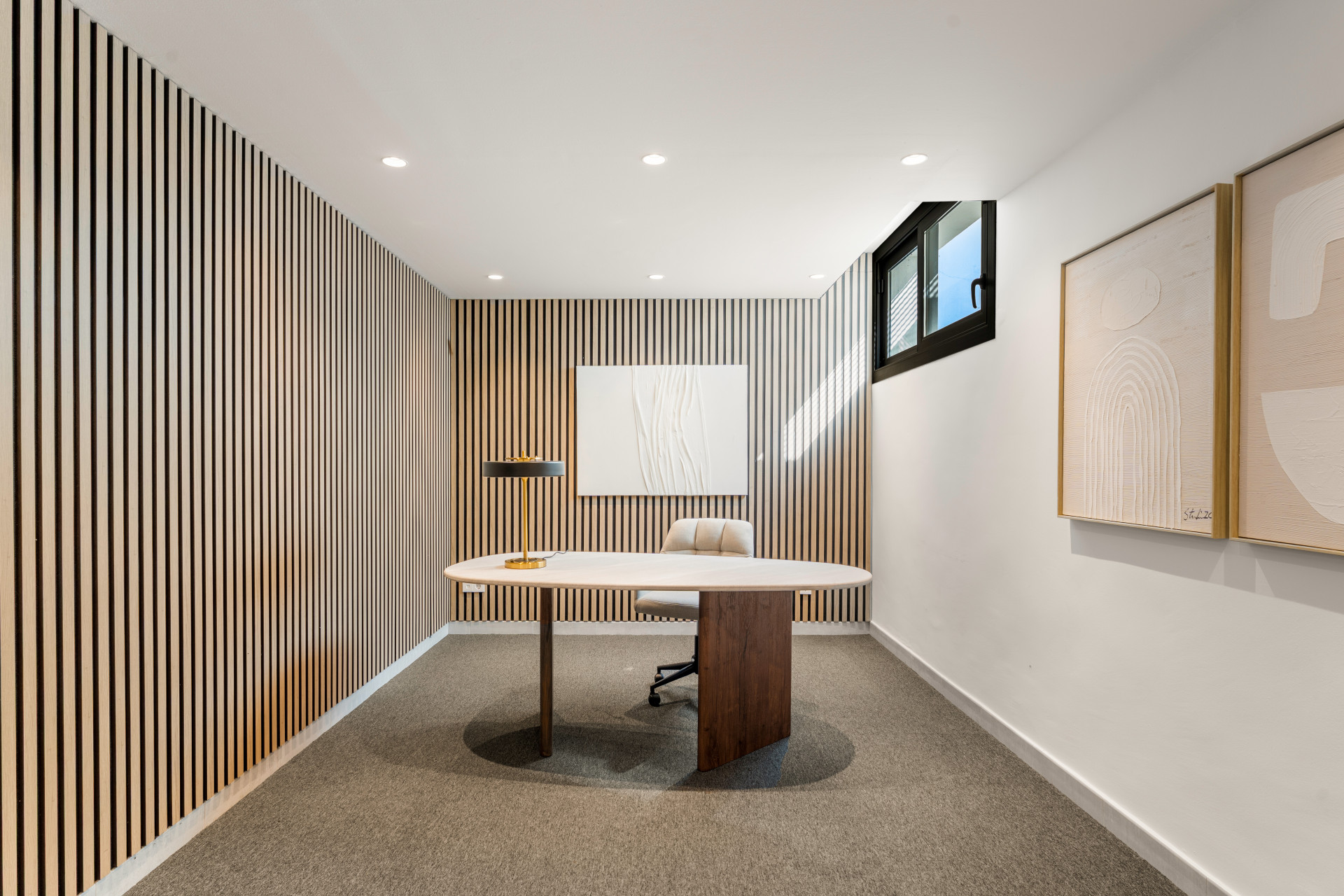 Contemporary office space with wooden wall panels and a round desk.