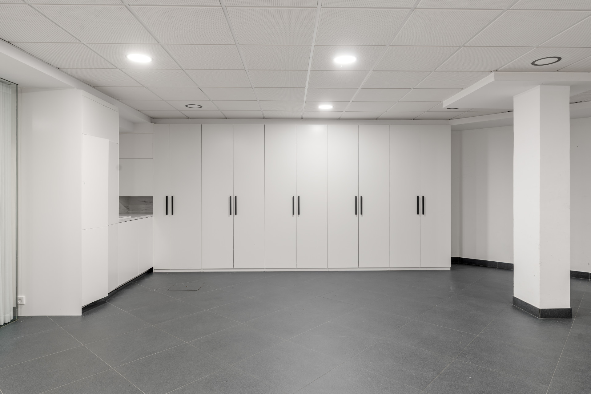 Interior view with built-in white cabinets and gray tile flooring