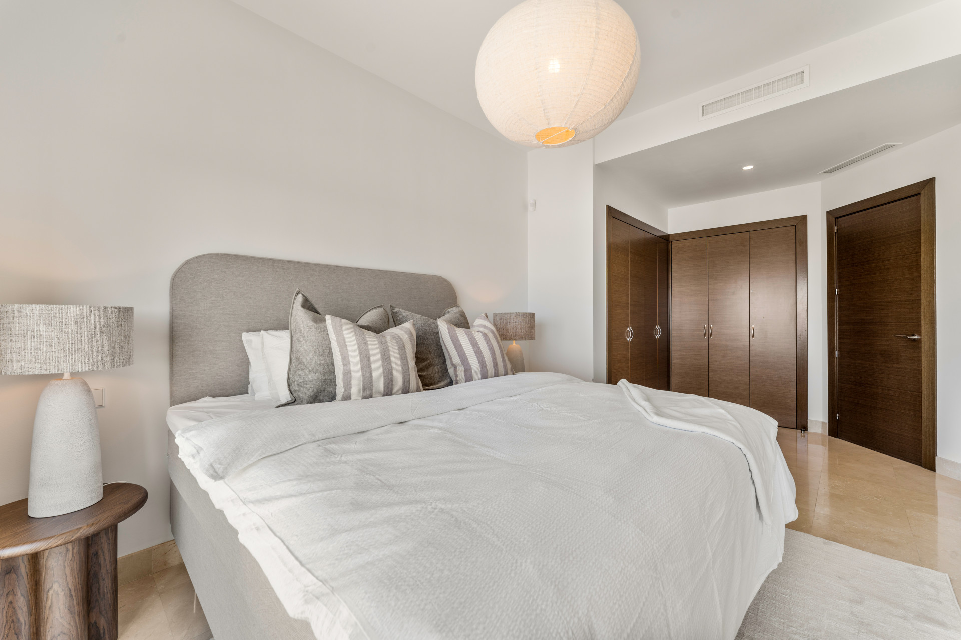 Spacious bedroom with bedside lamp, textured wall decor, and closet doors.