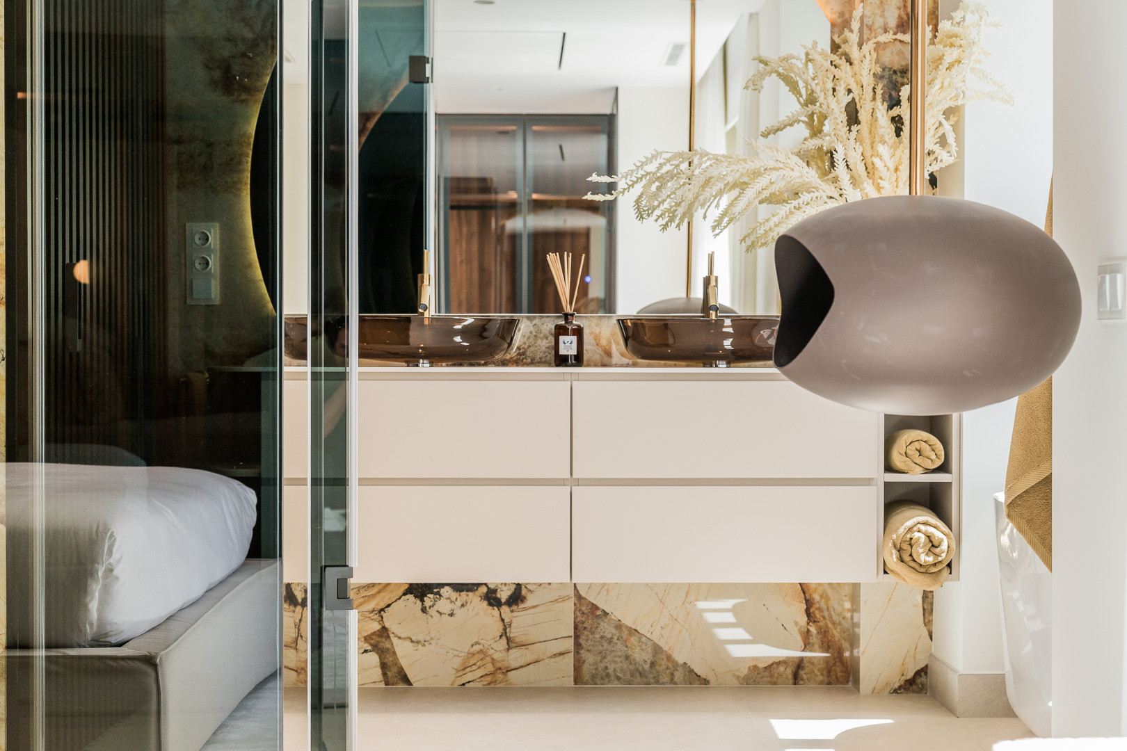 Bathroom with double vessel sinks, a vanity, marble accents, and a view into the adjacent bedroom.