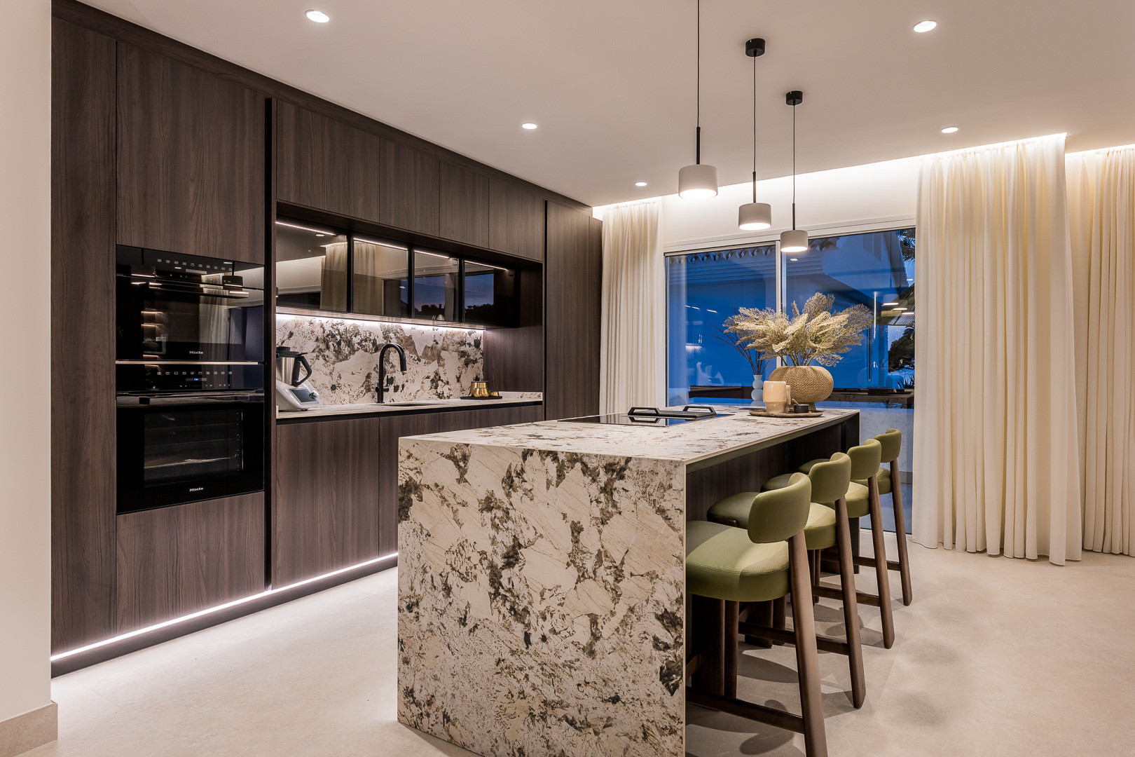 Wide shot of the modern kitchen and dining area, large window with sheer curtains visible.