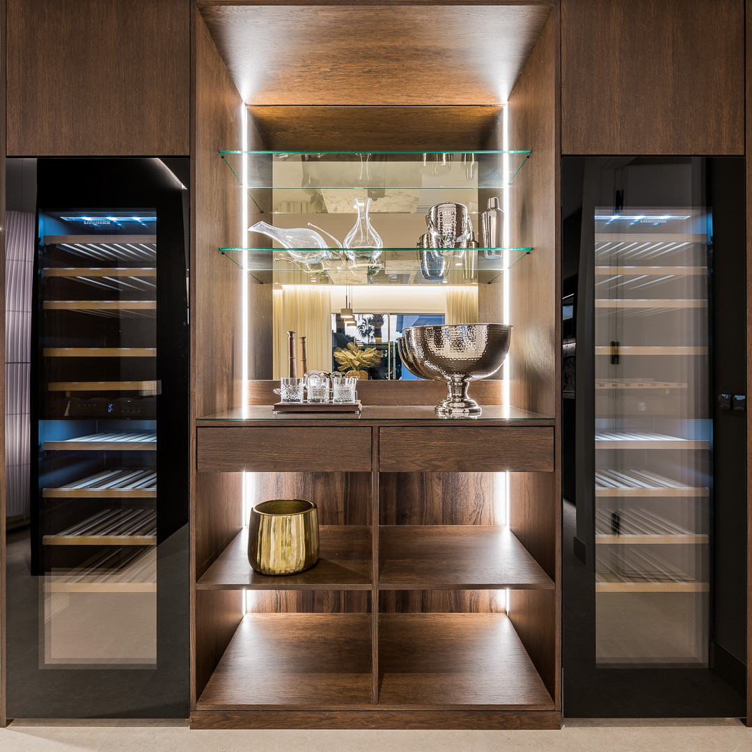 Integrated bar cabinet with glass shelves, under-shelf lighting, and two wine fridges.