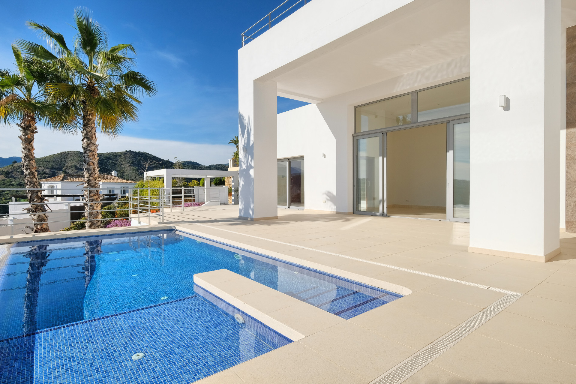 Outdoor patio with a rectangular pool and an adjacent white modern building.