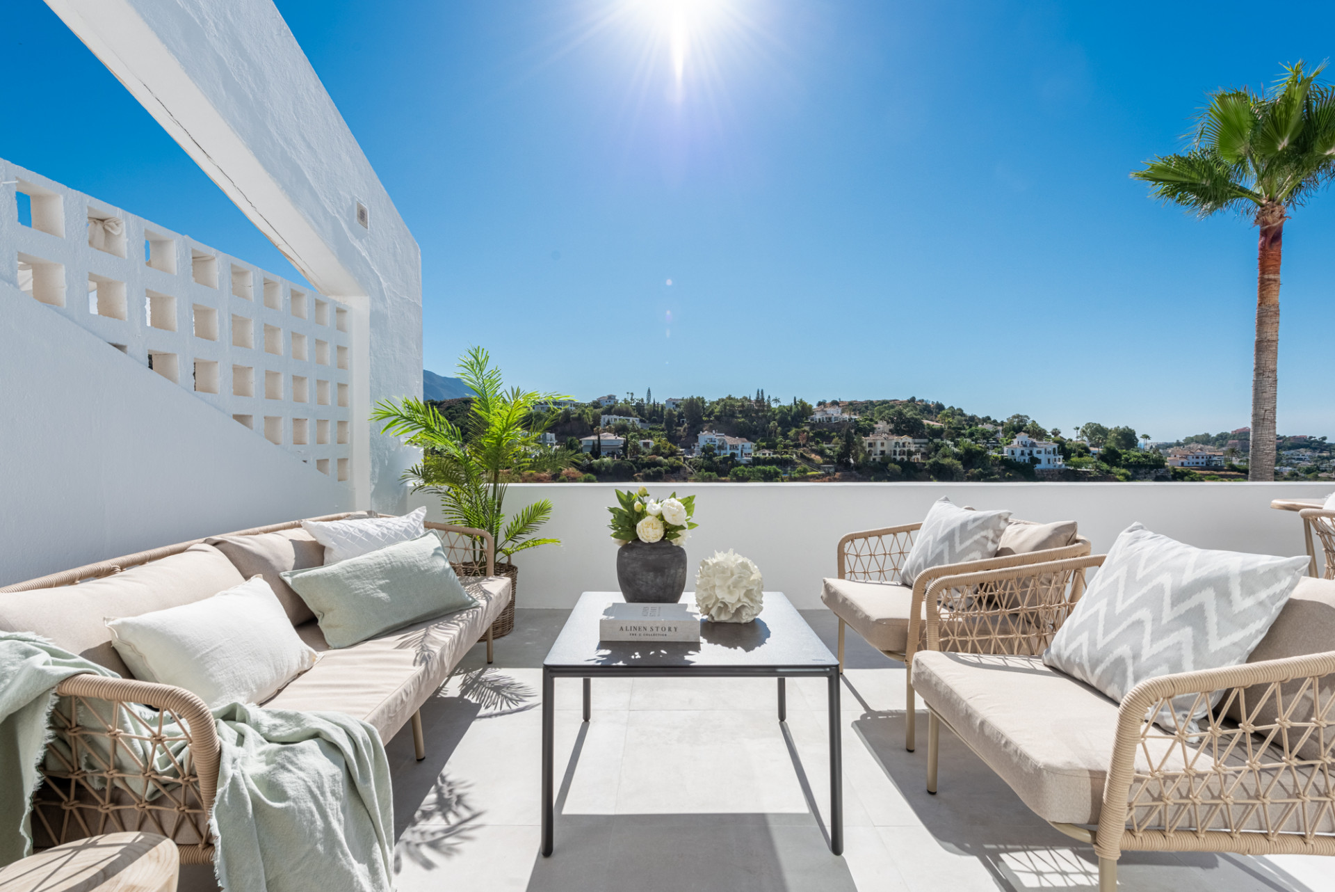 Rooftop terrace with outdoor lounge seating, coffee table, and panoramic views of hillsides and sky.