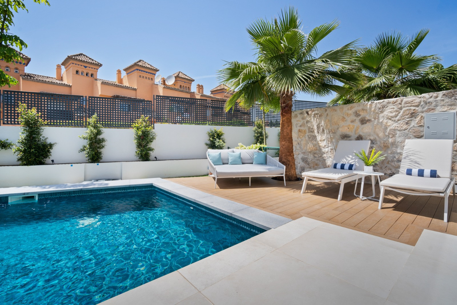 Pool surrounded by wooden decking and lounge chairs.