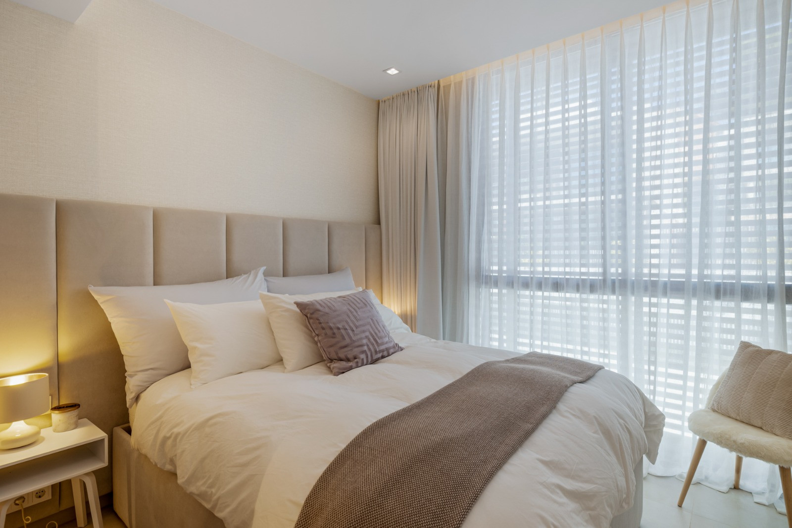 Bright bedroom with large windows and soft curtains.
