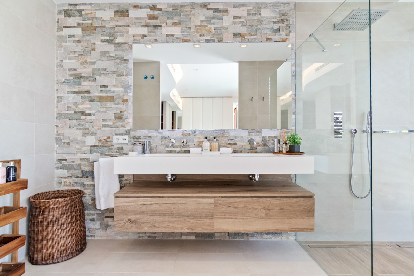 Modern bathroom with dual sinks, stone accent wall, and walk-in shower enclosure.