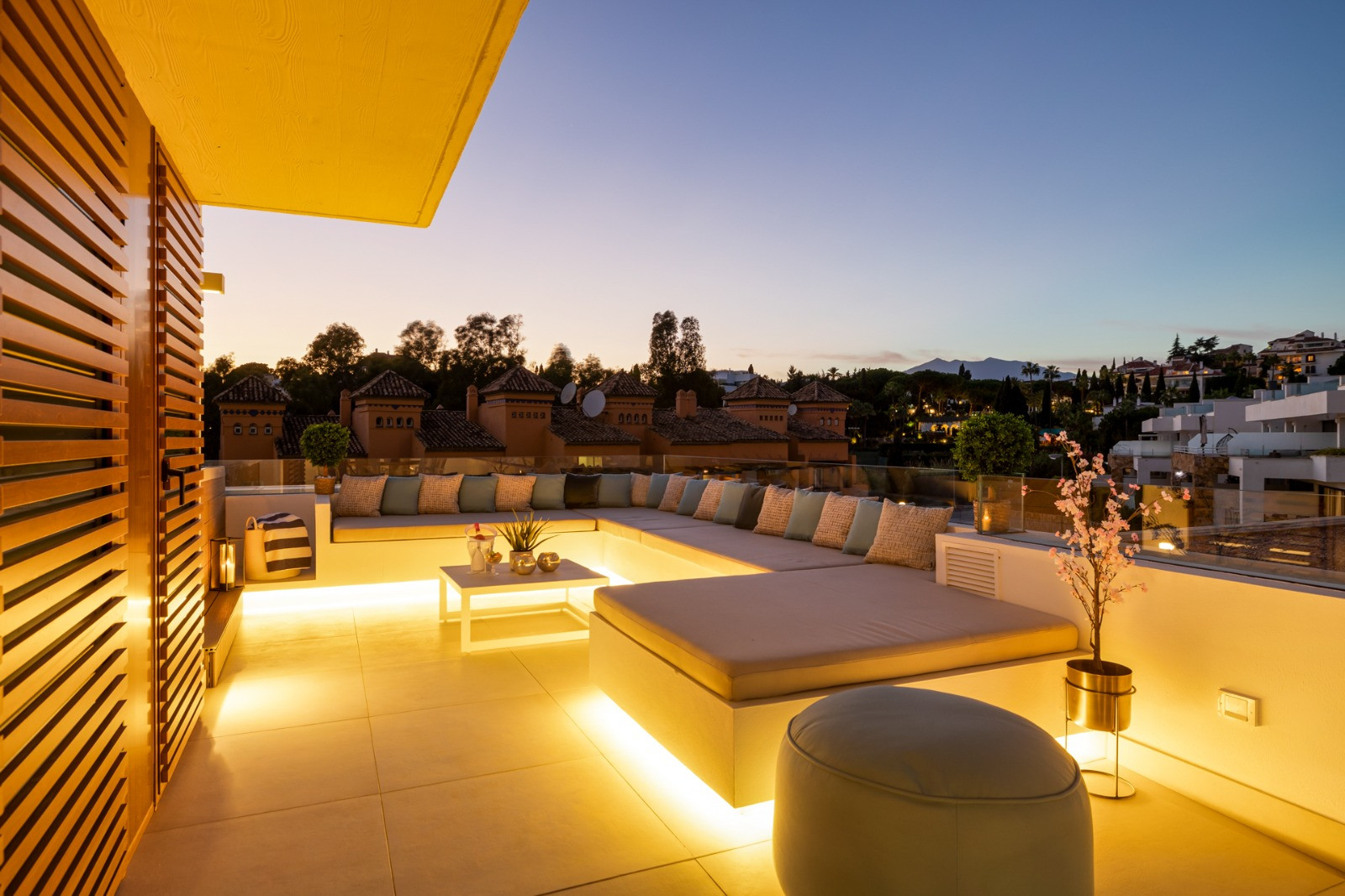 Evening view of the terrace with softly lit seating and decor, illuminated by warm lighting.