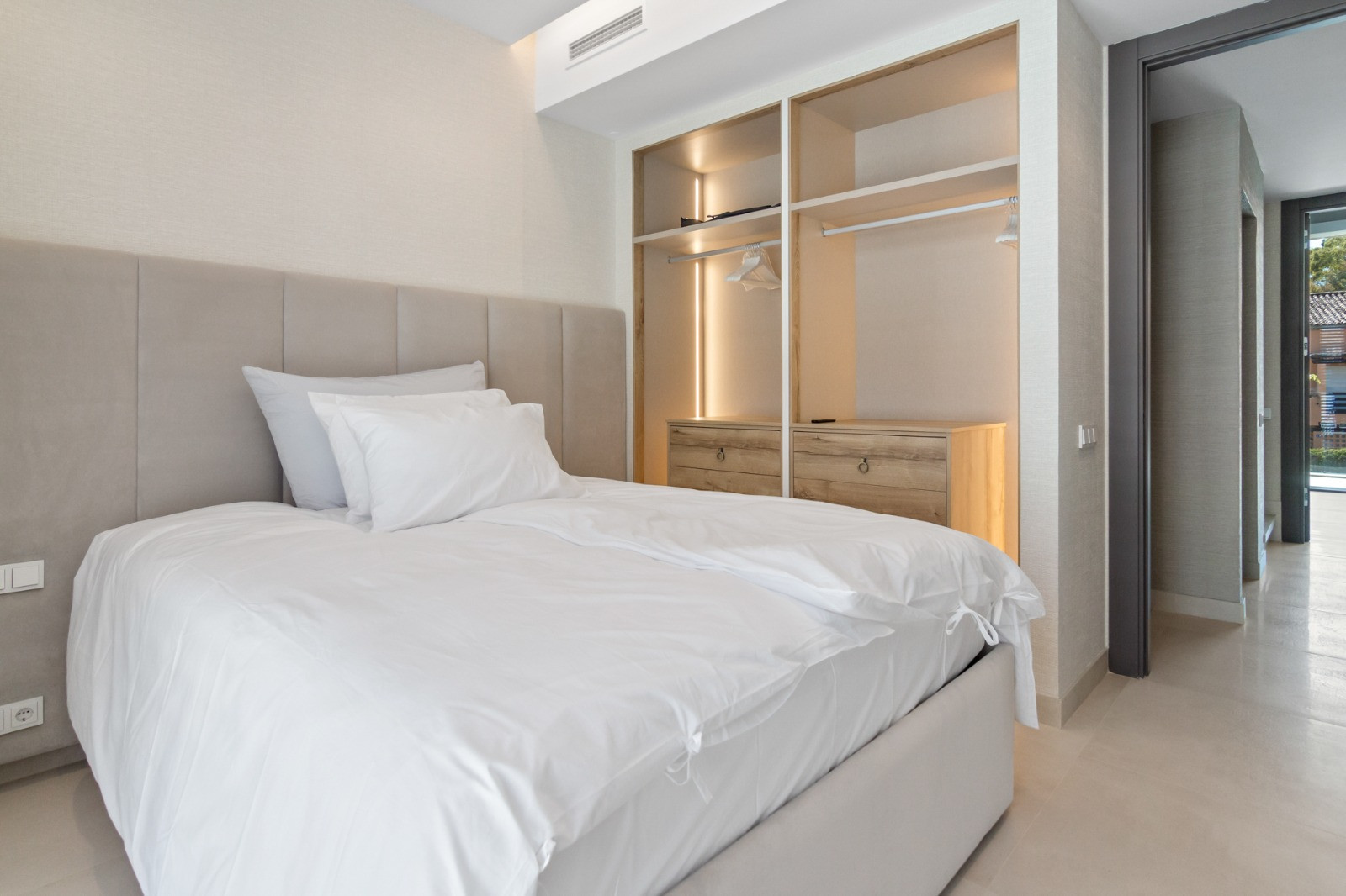 Cozy bedroom featuring a beige upholstered headboard and storage.