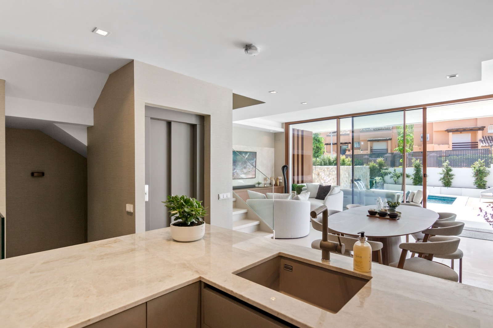 Open kitchen overlooking living area with dining table and glass doors opening to the garden.