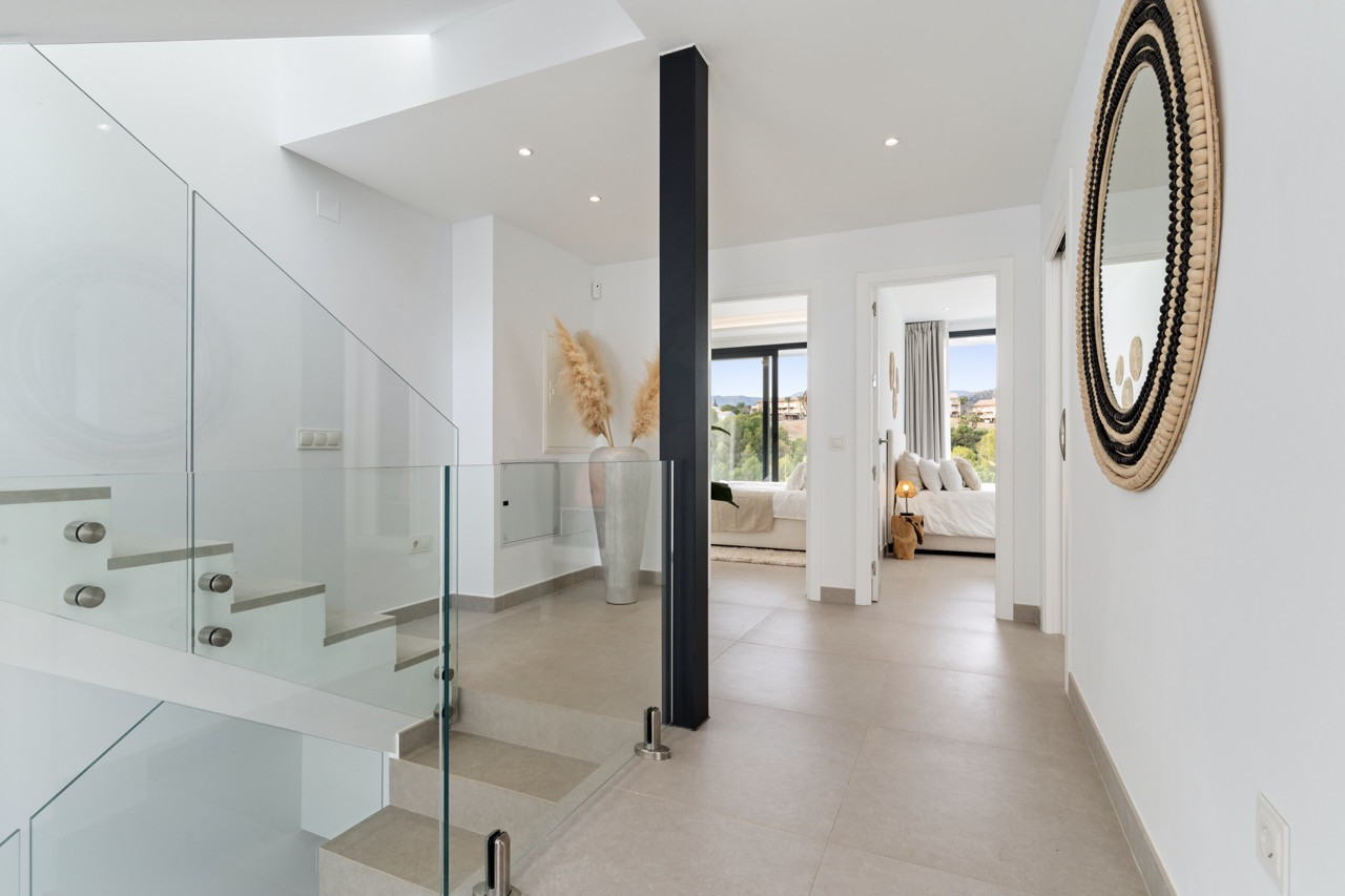 Spacious landing area with glass railings and a decorative vase, leading to other rooms.