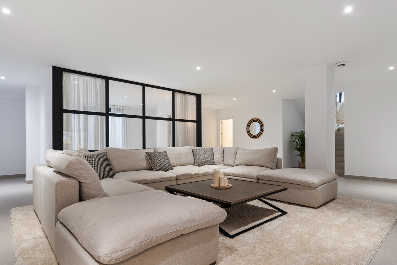 Open living space showcasing a large sectional sofa and a coffee table, with natural light flowing in.