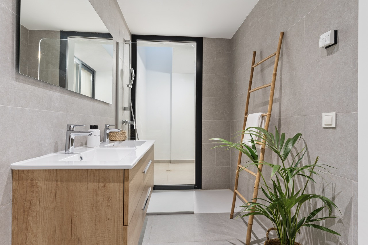 Modern bathroom with double sink, large mirror, and stylish shower area.