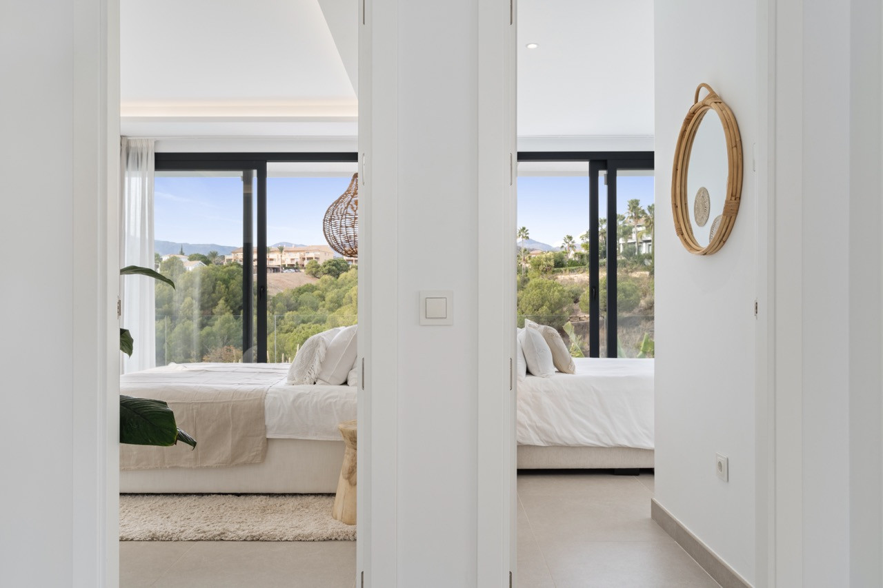 View of two bedrooms through an open doorway, highlighted by natural light and soft furnishings.