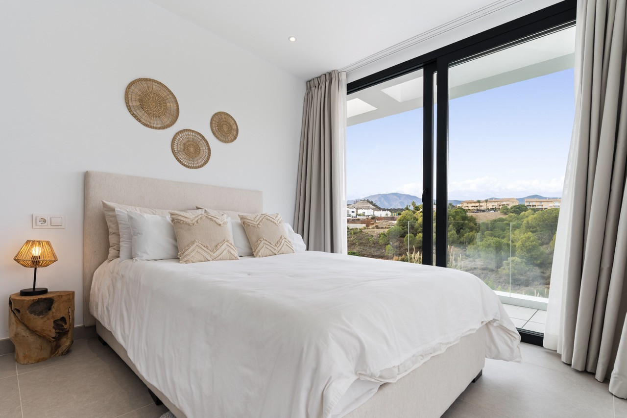 Modern bedroom with a large window, featuring a neutral palette and decorative wall art.
