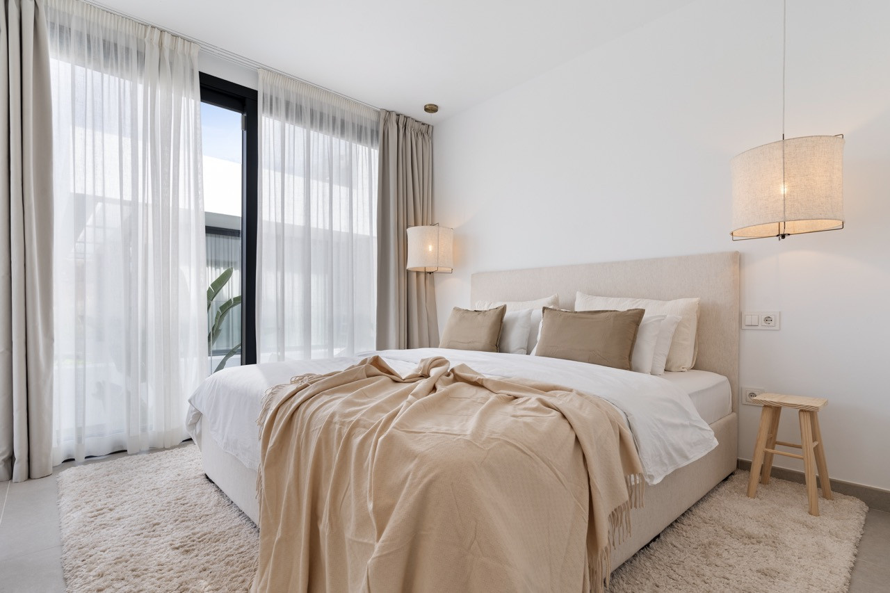 Cozy bedroom with a bed, light fixtures, and large windows.
