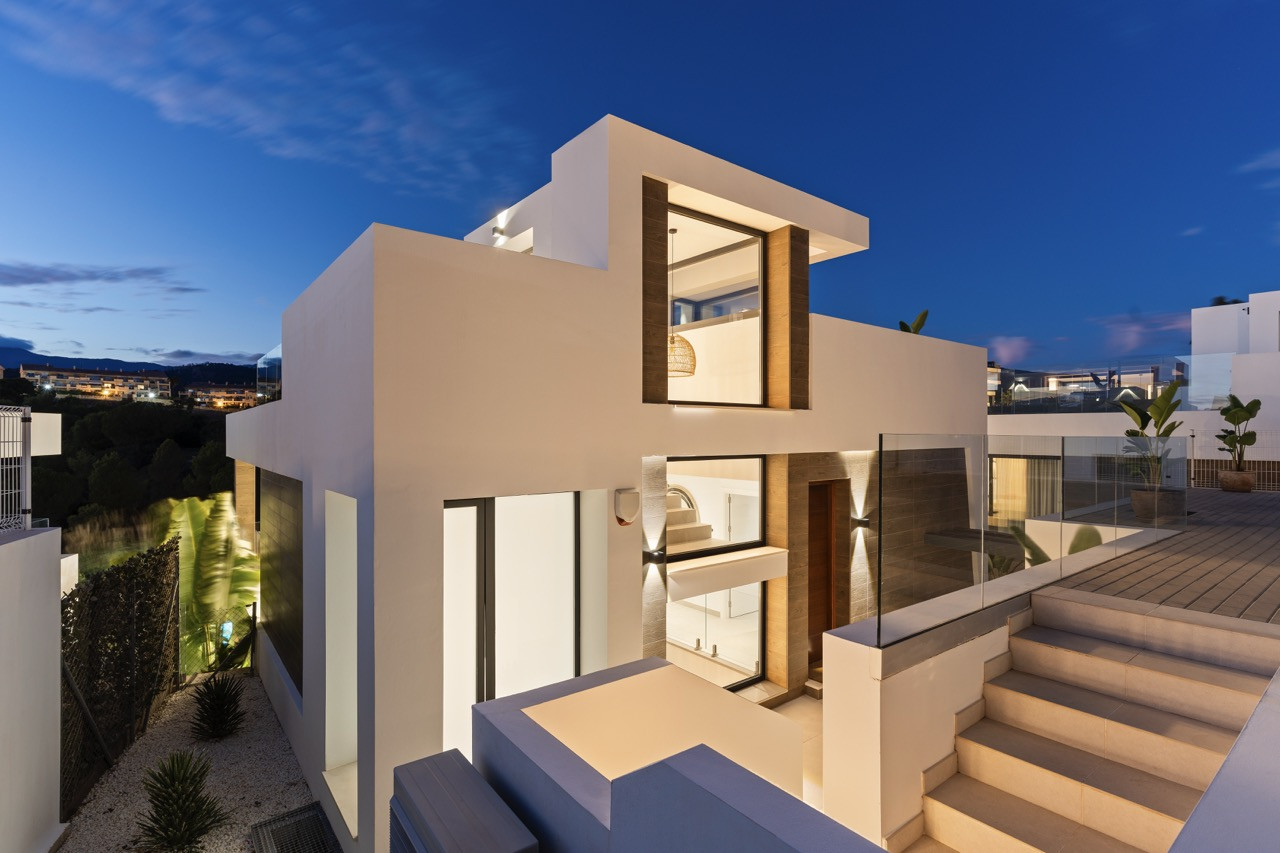 Exterior view showcasing white walls and glass paneling with city lights.