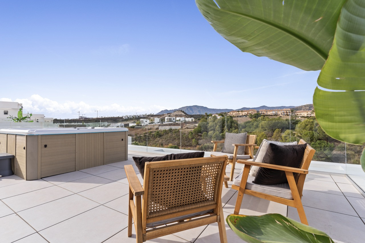 Rooftop terrace with spa, wooden chairs, and mountain views.