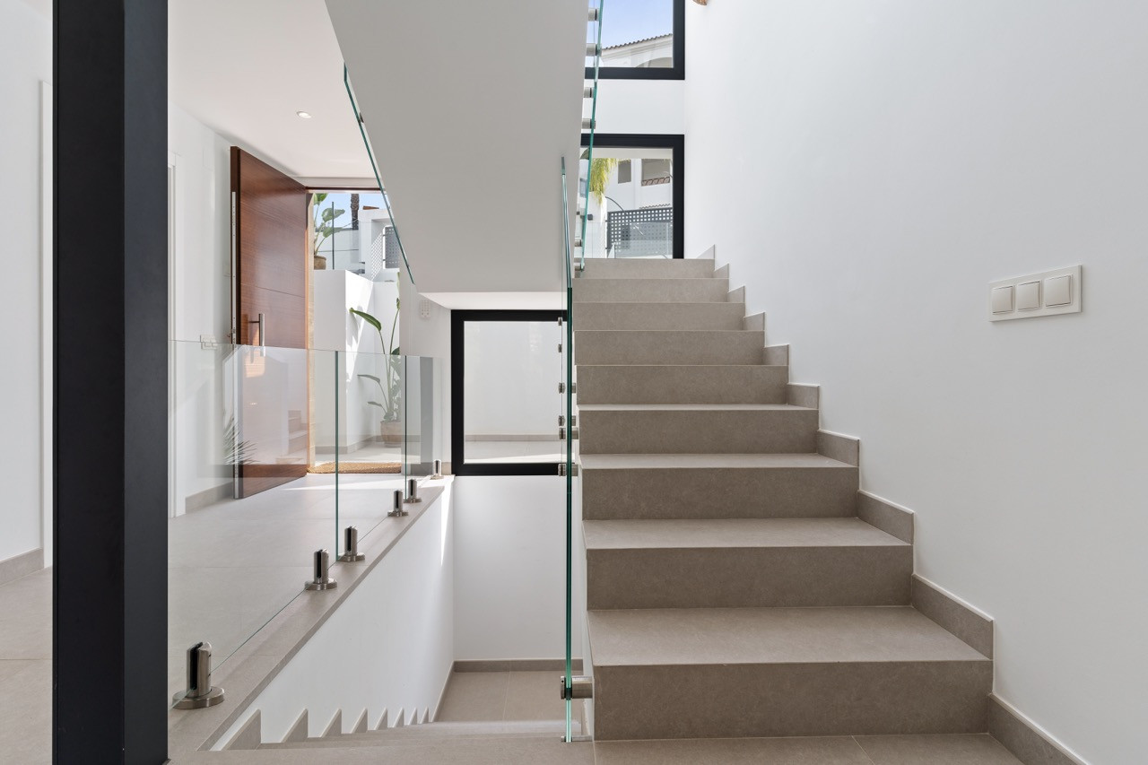 Well-lit staircase with glass railing leading to upper levels.