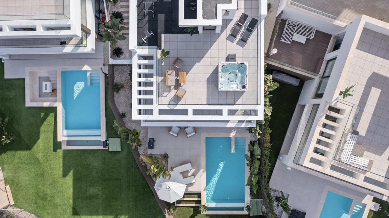 Top-down view displaying multiple pools and outdoor areas with seating on landscaped property.