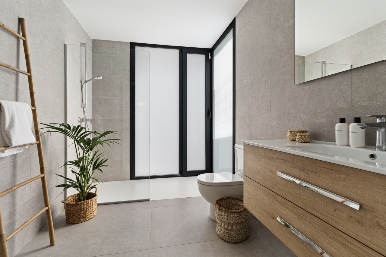 Modern bathroom featuring a shower, sink, and potted plant.