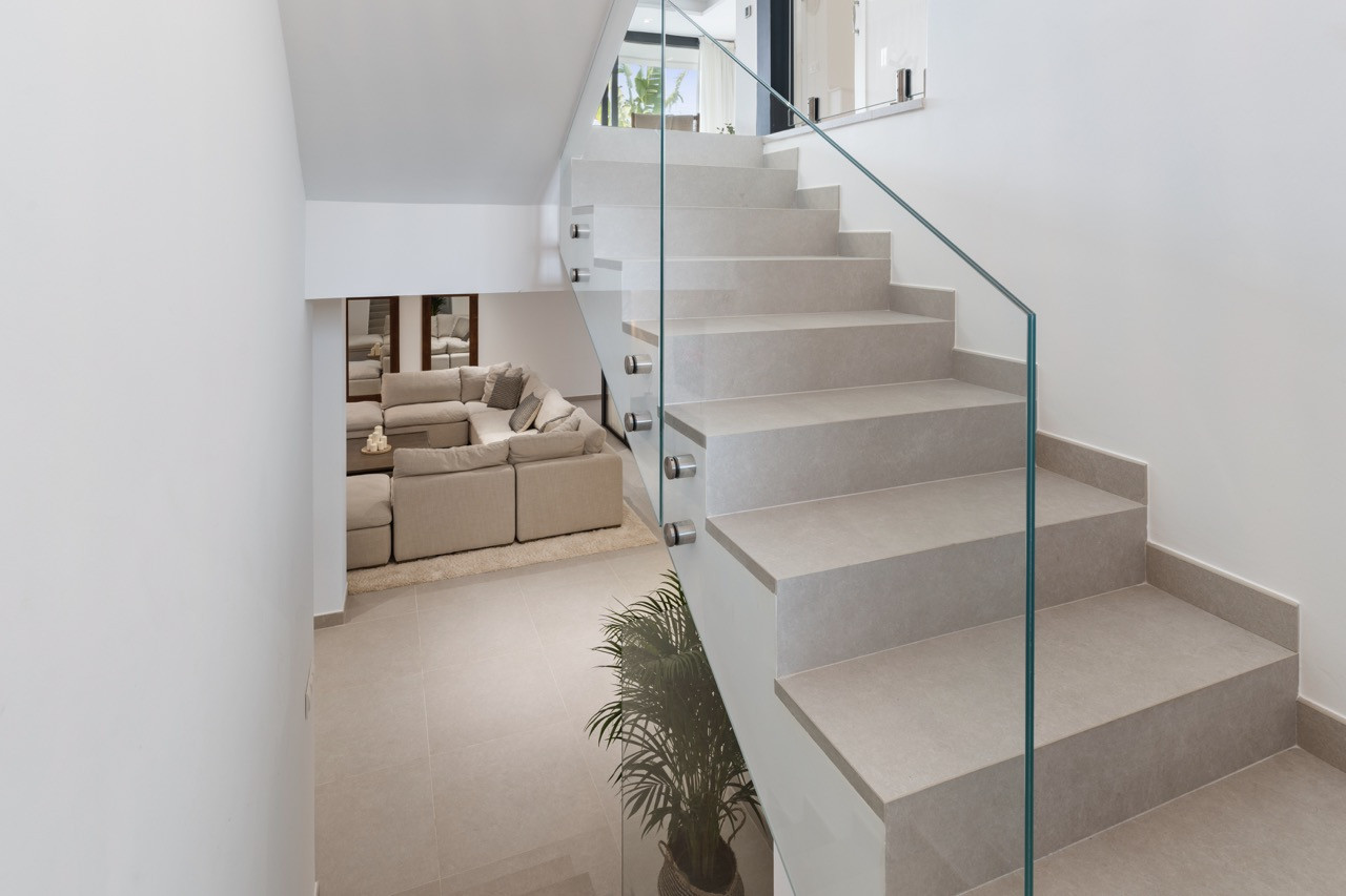 View of staircase with glass railing leading to lower level living area.
