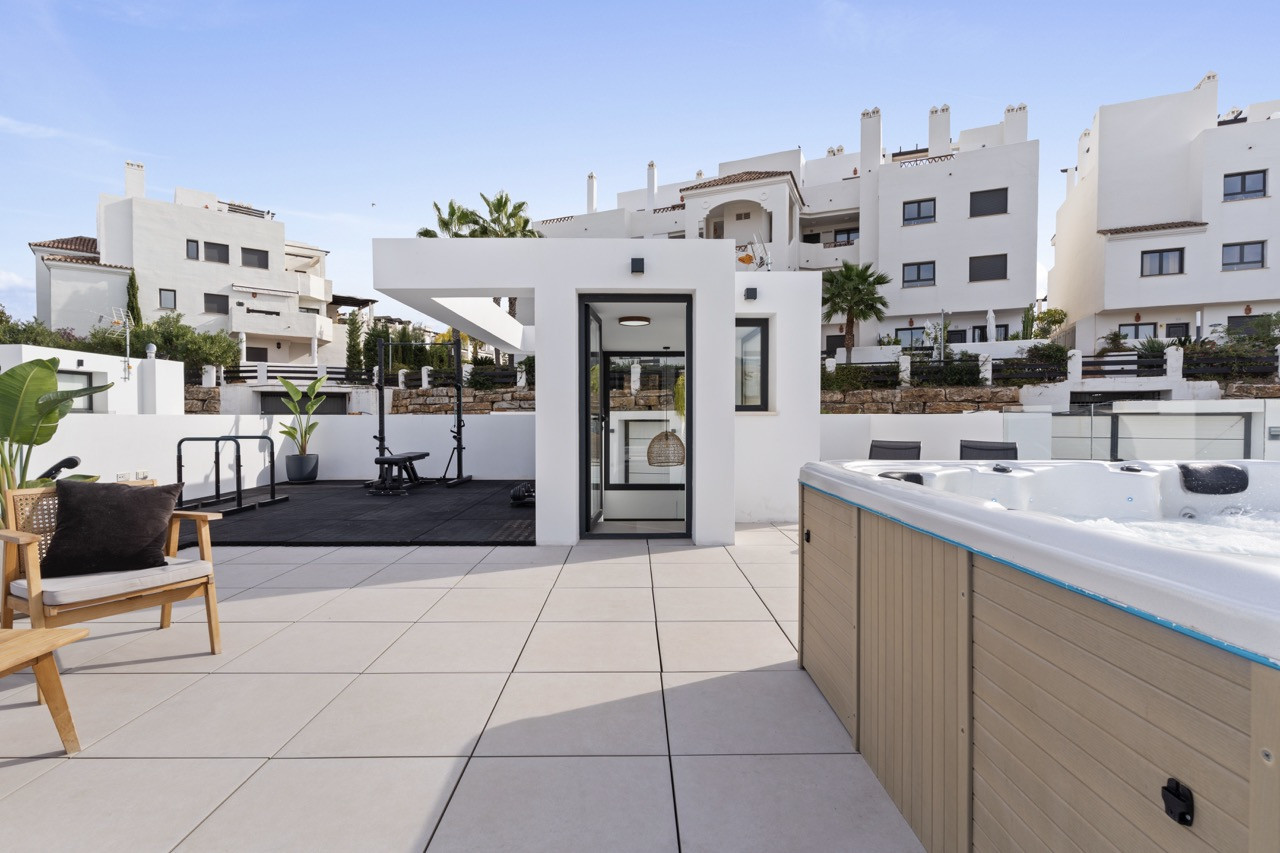 Gym area with equipment and adjacent spa on the terrace.
