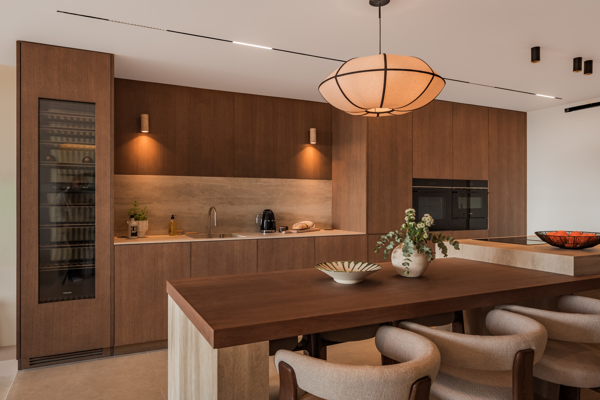 Modern kitchen view showing wood cabinets, built-in appliances, and a unique spherical light fixture.