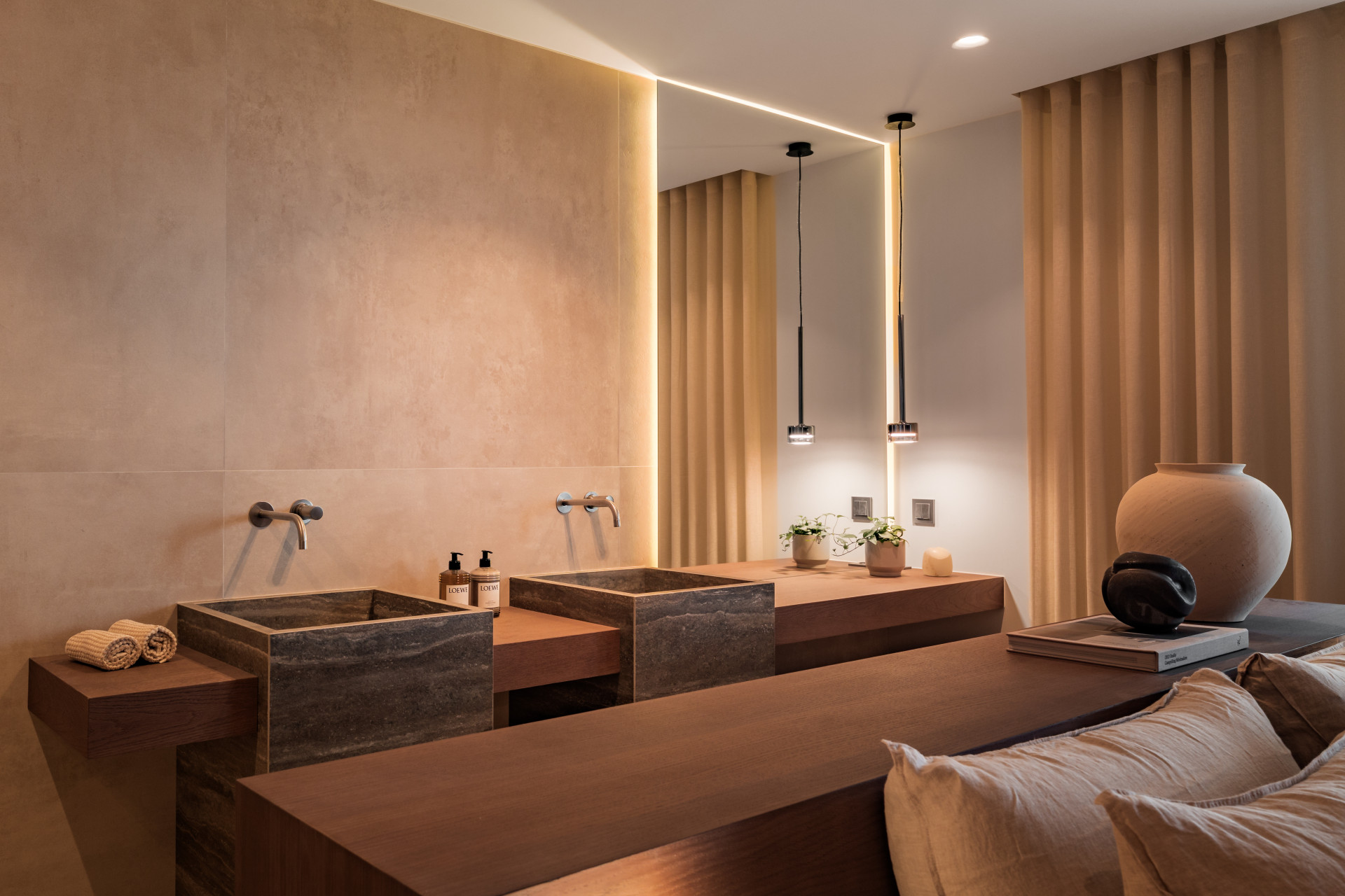 Double vanity bathroom with two dark stone sinks, a large mirror, and hanging pendant lights.