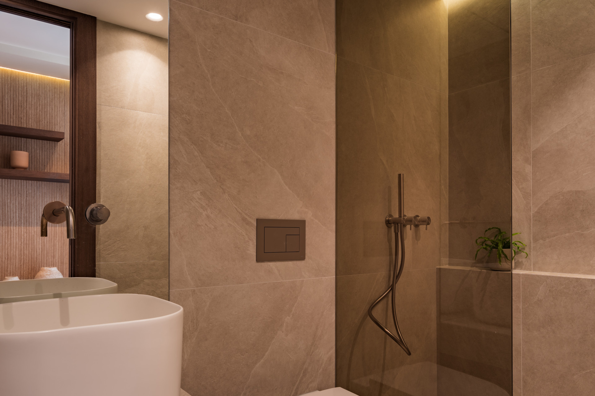Modern bathroom with a white sink, a flush toilet, a shower, and light beige tiled walls.