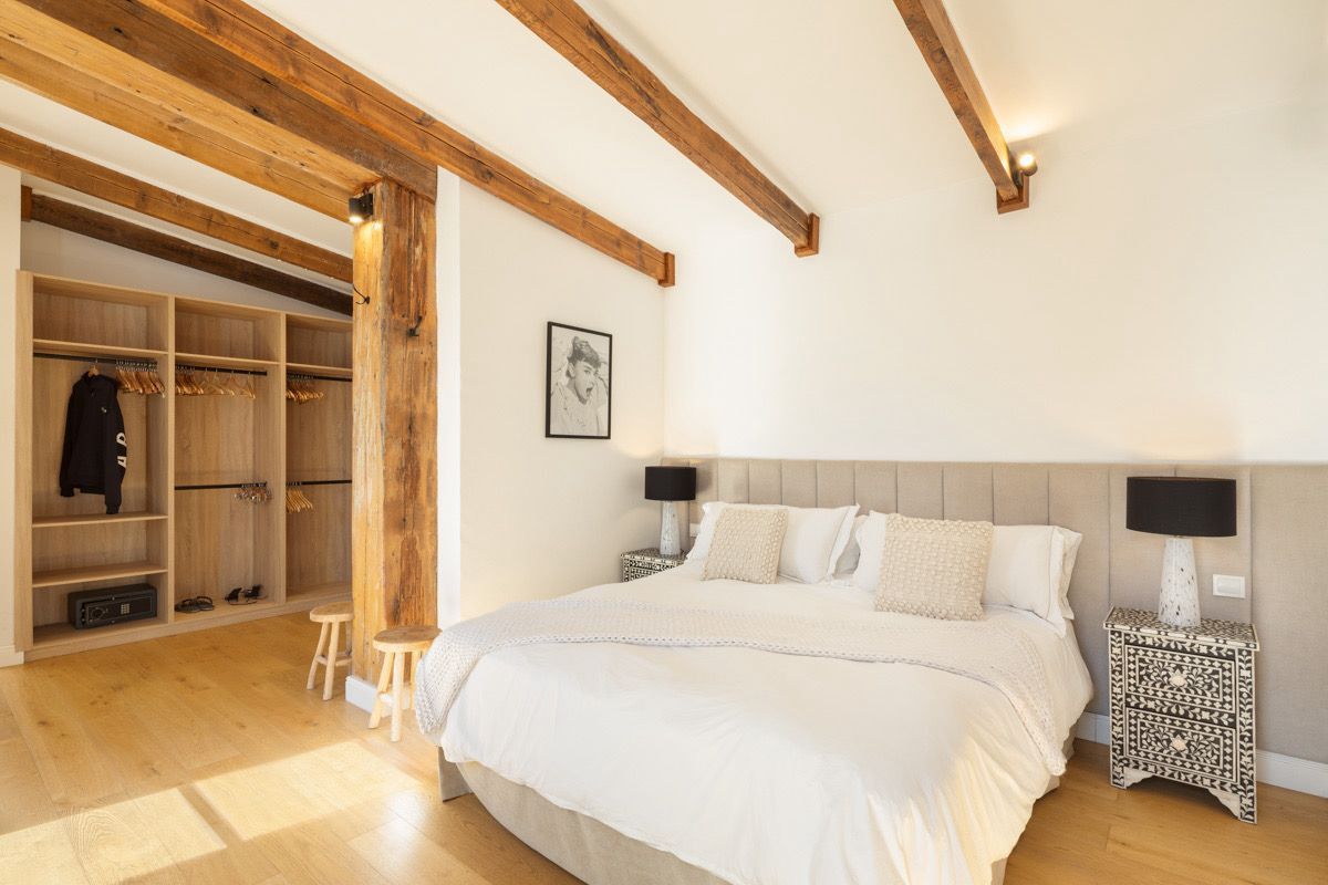 Bedroom with a large bed, two patterned nightstands, and an open wardrobe area with wood floors.
