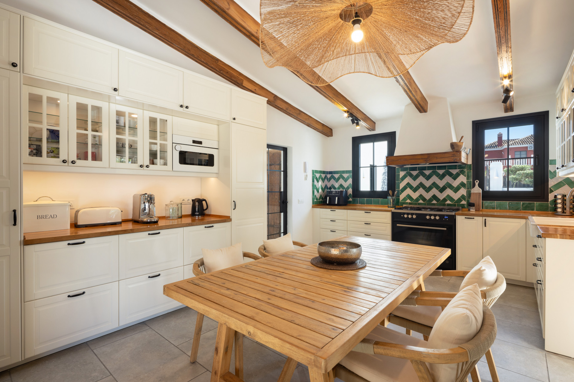 Kitchen with white cabinets, wood countertops, built-in appliances, and a central dining table.