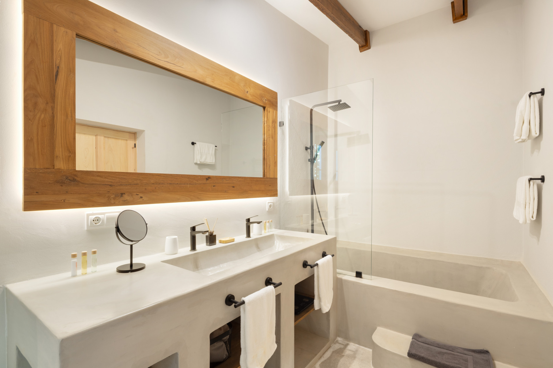 Bathroom with a double sink vanity, large wooden mirror, walk-in shower, and a built-in bathtub.