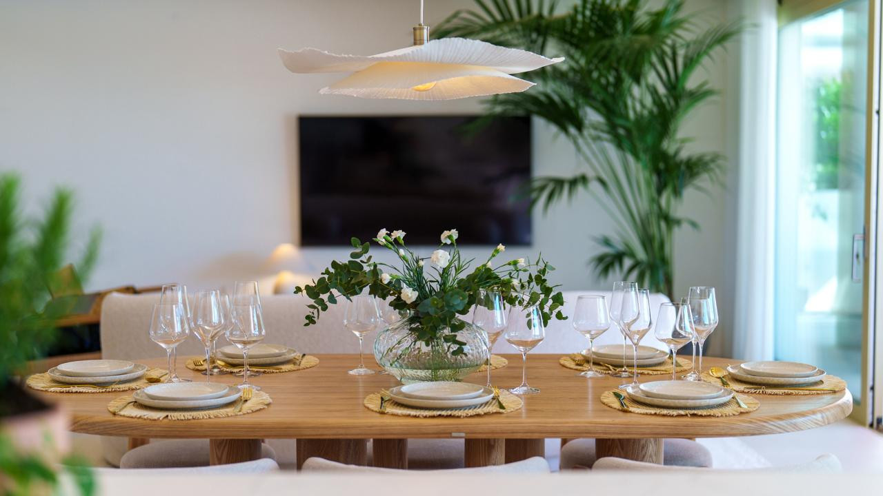 Close-up of a set dining table with a floral centerpiece, and a TV visible in the background.