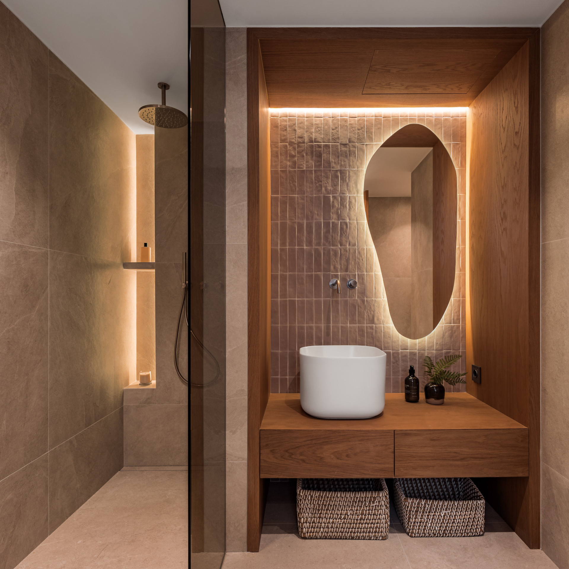 Bathroom vanity with a white vessel sink, backlit mirror, and open shower on the left.